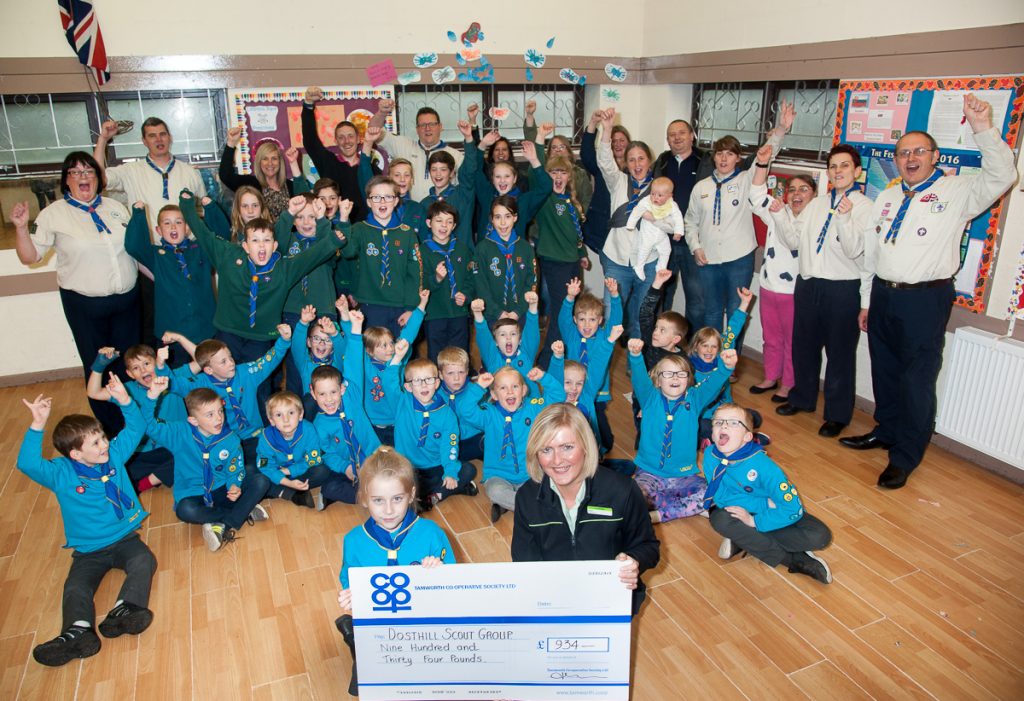 Darcii-Mai Cobden receives Community Dividend Fund cheque from Vicky Freeman, manager of Tamworth Co-op Dosthill convenience store, with Dosthill Scout Group members and leaders celebrating windfall.