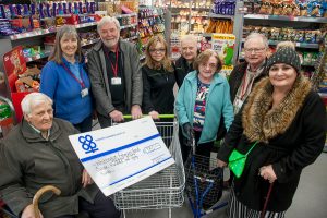 Members of Whittington and Fisherwick Good Neighbour Scheme receive Community Dividend Fund cheque at Whittington Co-op. Giant cheque is in trolley.