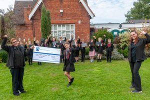 Whittington co-op staff presenting giant cheque to Howard Primary schoolchildren