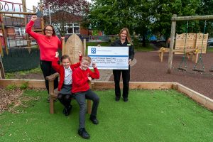 Glascote Co-op Community Dividend Fund cheque presented by manager to head teacher with two pupils cheering.