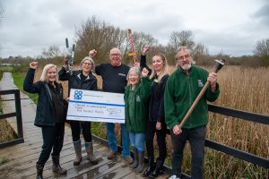 Bolehall Co-op manager presents cheque from Cash in the Bag scheme to nature reserve volunteers.